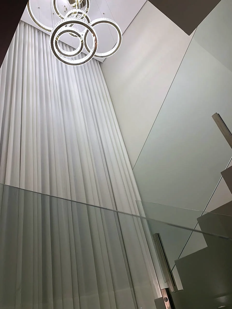 Cortina Wave em pé direito duplo com lustre de anéis, vista da escada, Artmari Decor SC